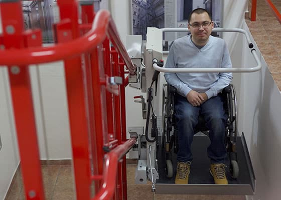 Mann im Rollstuhl fährt mit dem Lehner Stratos Plattformlift eine Treppe hoch – geprüft nach höchsten Sicherheitsstandards